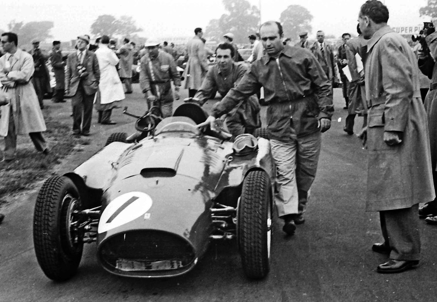 Fangio pushes his Lancia-Ferrari to the start line of the British Grand Prix in 1956