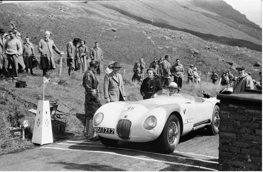 When Michael Head sold his C type Jaguar it was bought by Rosemary Vickers, seen here in duffel coat at Rest and Be Thankful hill climb in 1955 when she loaned it to Ecurie Ecosse driver Ninian Sanderson to run. (Graham Gauld)